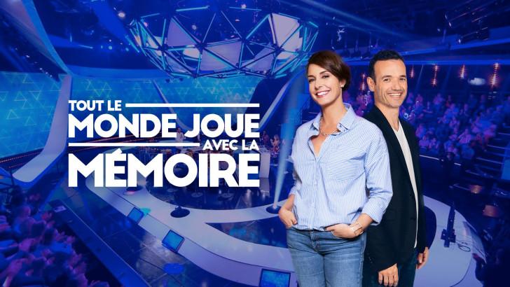 Photo de Julia Vignali et Fabien Olicard avec en fond le plateau. Le titre du jeu figure à leur gauche.